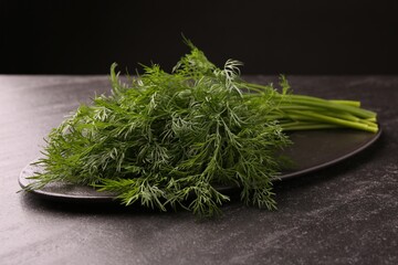 Sprigs of fresh dill on dark textured table, closeup