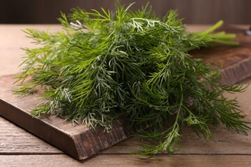 Board with sprigs of fresh dill on wooden table, closeup