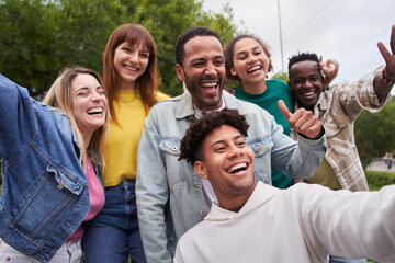 Cheerful group of friends taking smiling selfie. Group of young people having fun together outdoors at park in the city enjoying travel in vacation holidays.