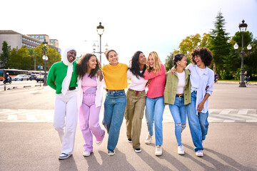 Group of young diverse only women friends walking relaxed and talking to each other and sharing a fun leisure time enjoying friendship together in city. Generation z youth community and people union