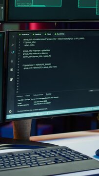 Vertical video Close up shot of dangerous hacking code running on high tech computer system monitors. Programming scripts shown on PC displays in empty criminal hideout used by hackers to commit