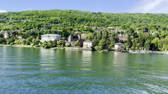 Scenic video of the Baveno and Stresa shoreline on Lake Maggiore, heading towards Isola dei Pescatori and Isola Bella on a sunny day in Verbano-Cusio-Ossola, Piedmont, Italy