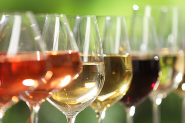 Different tasty wines in glasses against blurred background, closeup