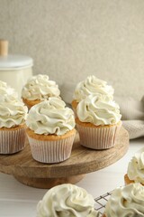 Tasty vanilla cupcakes with cream on white wooden table