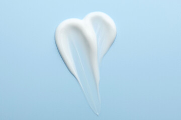 Sample of face cream on light blue background, top view
