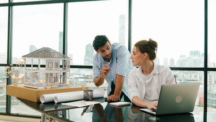 Smart architect engineer inspect house model while colleague using laptop analysis data....