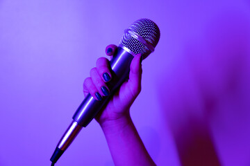 close-up shot of a hand holding a microphone in purple and pink lights