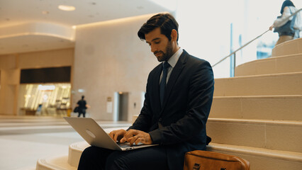 Skilled investor working or planing strategy by using laptop at stair. Professional business man...