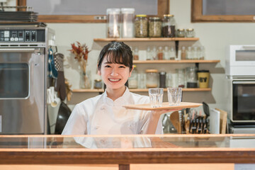 カフェ・飲食店の厨房で水を持つ調理師のアジア人女性
