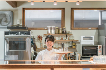 カフェ・飲食店の厨房で水を持つ調理師のアジア人女性
