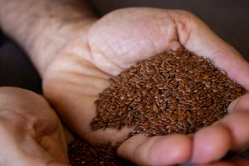 Hands holding flax seeds. Very close-up photo.Source of fiber and healthy oils