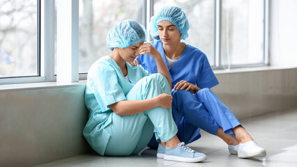 Female doctor calming her stressed colleague in clinic