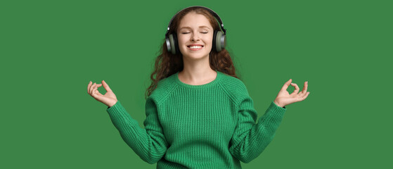 Portrait of relaxed young woman meditating while listening to music on green background