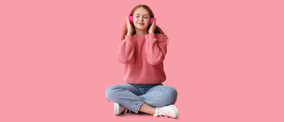 Portrait of relaxed young woman meditating while listening to music on pink background
