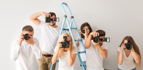 Group of young photographers on light background