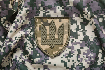 Military badge of Ukrainian army with trident on camouflaged uniform