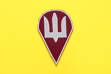Military badge of Ukrainian army with trident on yellow background