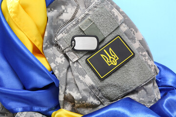 Military uniform with badge of Ukrainian army, tag and Ukraine flag on turquoise background