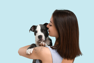 Beautiful young woman with cute staffordshire terrier puppy on blue background