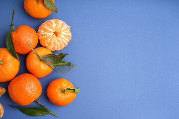 Tasty tangerines with leaves on blue background