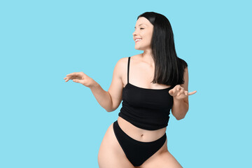 Body positive young woman in underwear on blue background