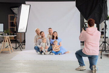 Fototapeta premium Male photographer taking picture of big family in studio