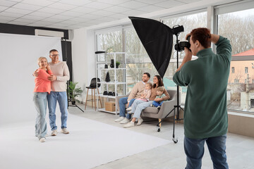 Male photographer taking picture of family in studio