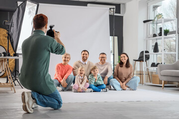 Male photographer taking picture of big family in studio, back view