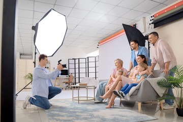 Male photographer taking picture of big happy family in studio