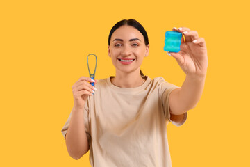 Beautiful young happy woman with dental floss and tongue scraper on yellow background