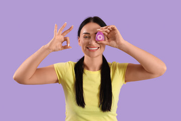 Beautiful young happy woman with dental floss showing OK gesture on purple background