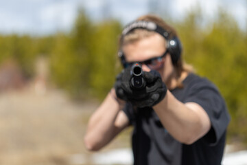 Young man aiming shotgun at you.  Front view. Focus on muzzle.