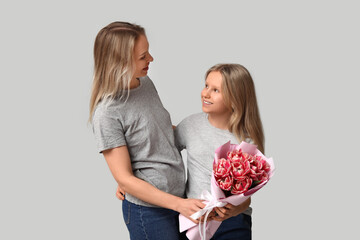 Cute little girl with her mom and bouquet for Mother's Day on white background