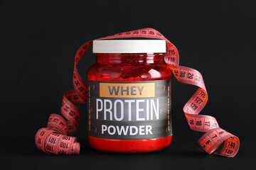 Bottle with protein powder and measuring tape on dark background