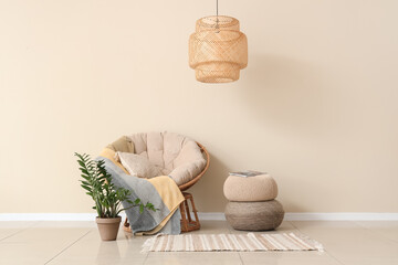 Interior of light living room with armchair, plant and poufs