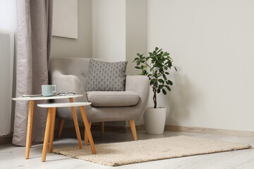 Interior of light living room with grey armchair and tables