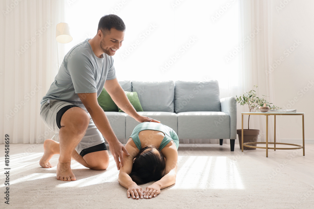 Canvas Prints Sporty young couple practicing yoga together in living room