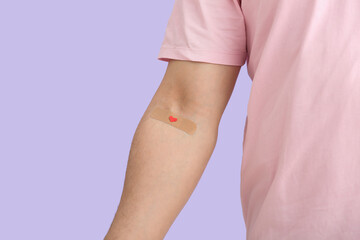 Blood donor with applied medical patch on lilac background, closeup