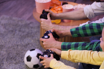 Little children with their father playing video game at home in evening, closeup