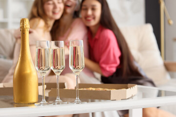 Bottle with glasses of champagne and pizza on table at Hen Party, closeup