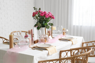 Beautiful table setting with pink roses and candles for wedding celebration in room