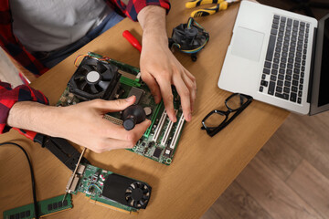 Male technician repairing computer board at table in service center, closeup