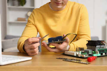 Young technician repairing computer at table in service center, closeup