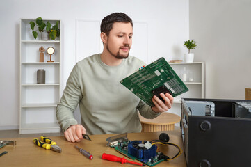 Male technician repairing computer board at table in service center