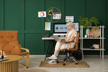 Young female graphic designer working with laptop in office