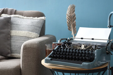 Vintage typewriter with feather on table in living room, closeup