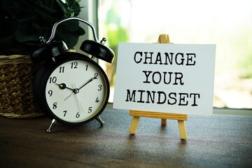 Change your mindset text message on paper card with wooden easel on wooden table background,...