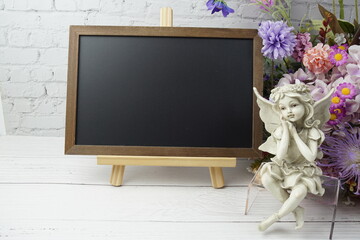 Empty chalkboard mock up space for text message with flower bouquet and home decorations on wooden background