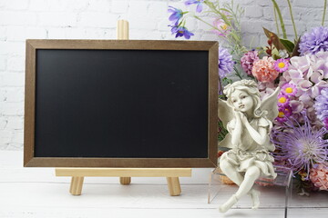 Empty chalkboard mock up space for text message with flower bouquet and home decorations on wooden background