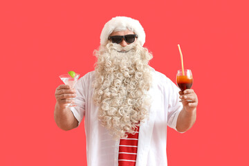 Santa Claus with cocktails on red background. Christmas in July